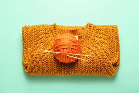 Yarn with knitting needles and sweater on color backgroundの写真素材