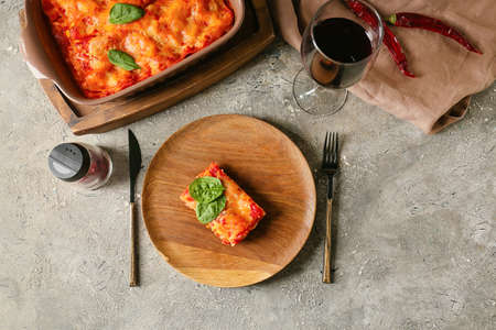 Composition with tasty tomato lasagna and glass of wine on grunge backgroundの写真素材