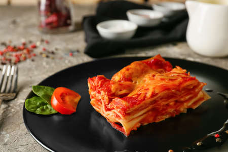 Plate with piece of tasty tomato lasagna on table, closeupの写真素材