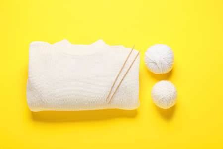 Yarn with knitting needles and sweater on color backgroundの写真素材