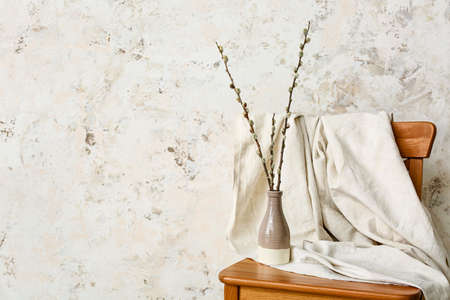 Vase with willow branches on chair near light wallの写真素材