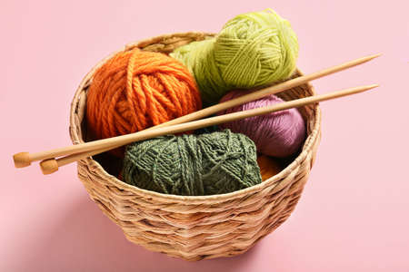 Basket with knitting yarn and needles on color backgroundの写真素材