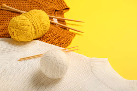 Yarn with knitting needles and sweaters on color backgroundの写真素材