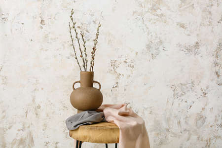 Vase with willow branches on table near light wallの写真素材