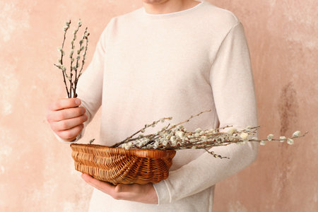 Young man with willow branches on color backgroundの写真素材