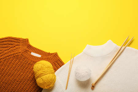 Yarn with knitting needles and sweaters on color backgroundの写真素材