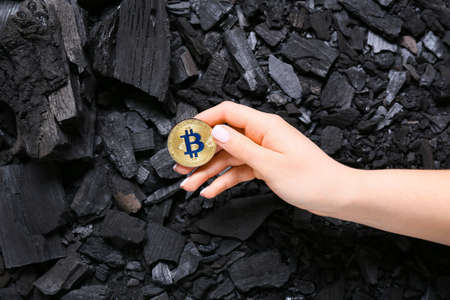 Woman with golden bitcoin on coal backgroundの写真素材
