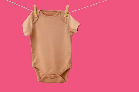 Baby clothes hanging on rope against color backgroundの写真素材