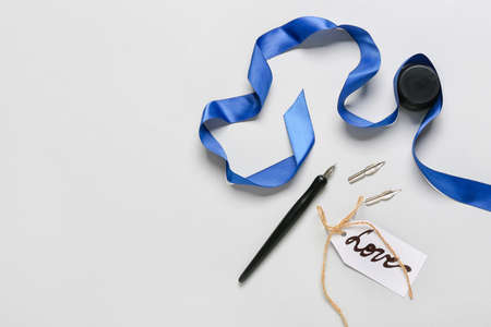 Nib pen with ink, ribbon and word LOVE on light background