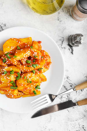 Plate with honey chili potato on light backgroundの写真素材