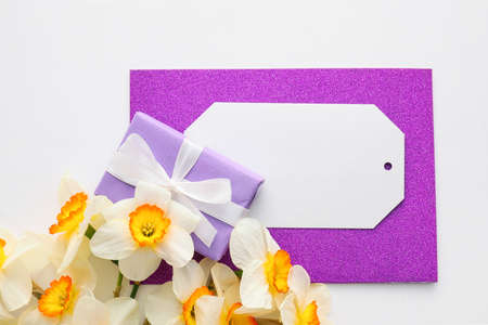 Beautiful daffodils, gift box and blank card on white background
