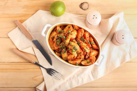 Baking dish with honey chili potato on wooden background