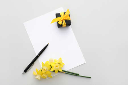 Beautiful daffodils, pen and blank paper sheet on white backgroundの写真素材
