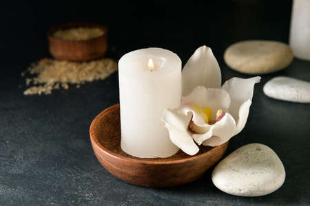 Bowl with flower and burning candle on dark backgroundの写真素材