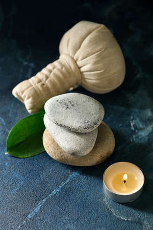 Stack of spa stones, candle and herbal bag on blue backgroundの写真素材