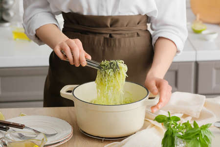 Woman cooking tasty pesto pasta at tableの写真素材