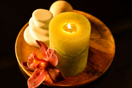 Tray with spa stones, candle and flower on dark backgroundの写真素材