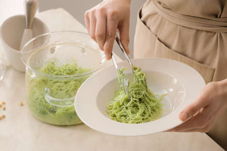 Woman cooking tasty pesto pasta at table, closeupの写真素材