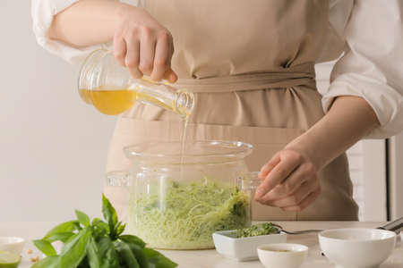 Woman cooking tasty pesto pasta at table