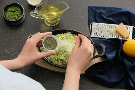 Woman cooking tasty pesto pasta at table