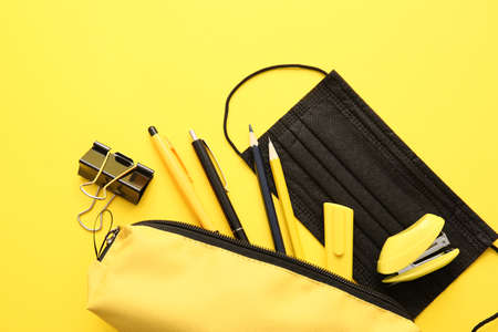 Pencil case with stationery on color background