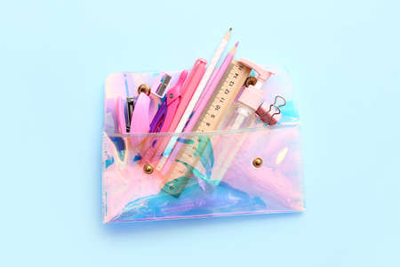 Pencil case with stationery on color background