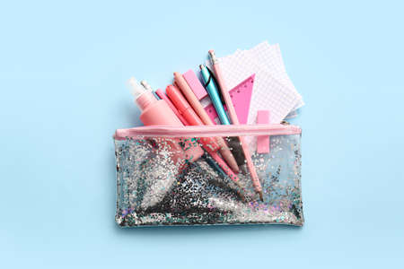 Pencil case with stationery on color background