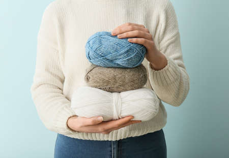 Woman holding knitting yarn on color backgroundの写真素材