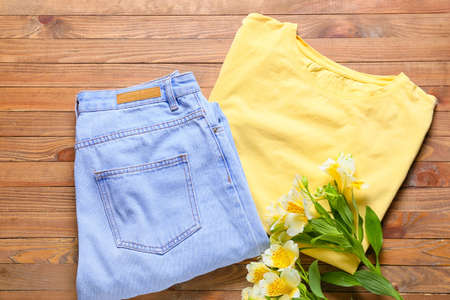 Stylish t-shirt, jeans and flowers on wooden backgroundの写真素材