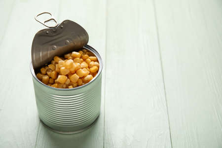 Tin can with corn kernels on color wooden backgroundの写真素材