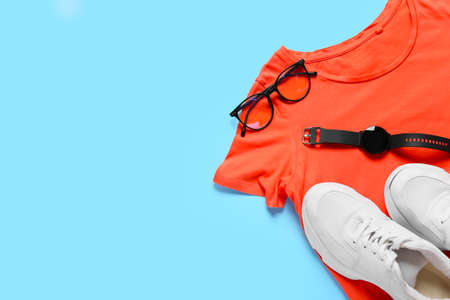 Stylish t-shirt, shoes, wrist, watch and eyeglasses on color background, closeupの写真素材
