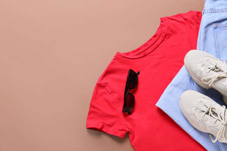 Stylish t-shirt, jeans, sunglasses and shoes on color backgroundの写真素材