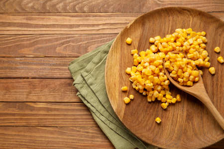 Plate with corn kernels on wooden background