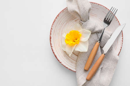 Beautiful table setting with narcissus flower on white background