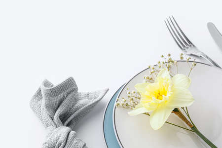 Beautiful table setting with narcissus flower on white background