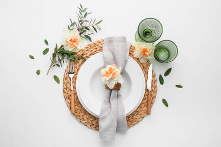 Beautiful table setting with narcissus flowers on white background