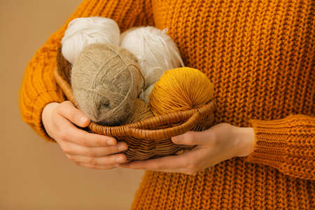 Woman holding basket with knitting yarn on color backgroundの写真素材