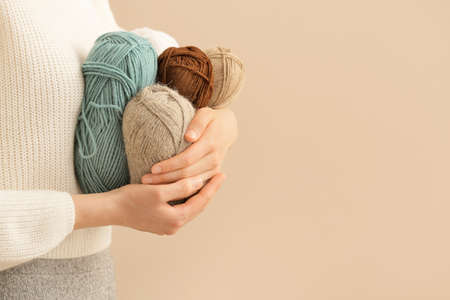 Woman with knitting yarn on color background