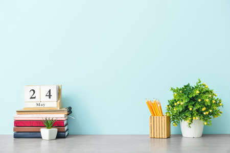 Stylish workplace with houseplant, notebooks and stationery near color wall