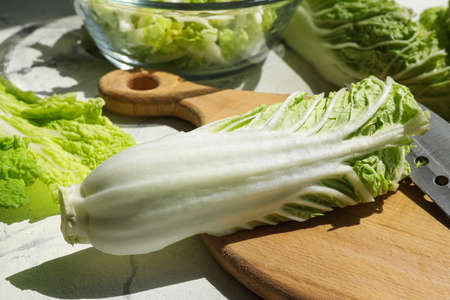 Board with fresh chinese cabbage on light background, closeup