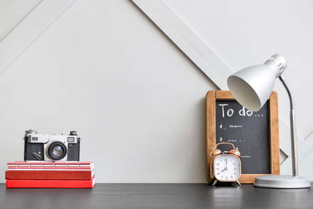 Stylish workplace with photo camera and modern lamp near color wall