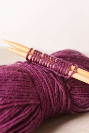 Purple knitting yarn and needles on light background