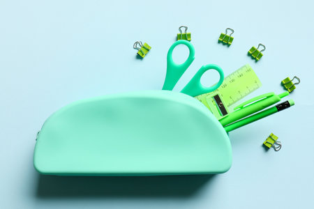 Pencil case and stationery on blue background
