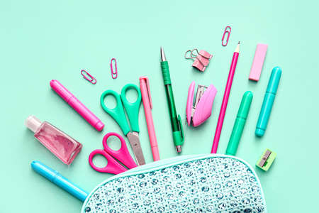 Composition with pencil case, stationery and sanitizer on color background, closeup