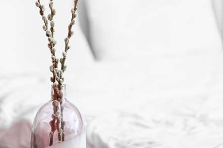 Vase with willow branches near bed in roomの写真素材