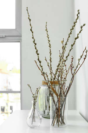 Vases with willow branches on table in roomの写真素材