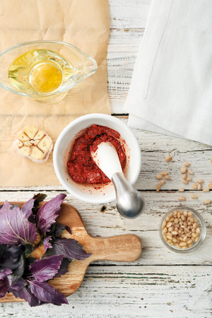 Mortar with tasty pesto sauce and ingredients on light wooden backgroundの写真素材