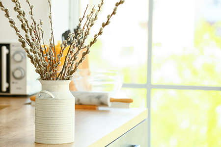 Vase with willow branches on table in kitchenの写真素材