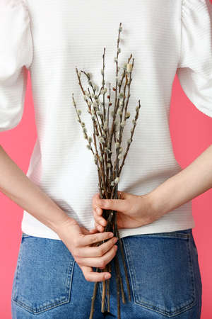 Woman with willow branches on color background