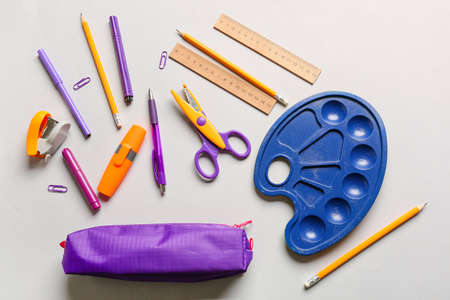 Pencil case, palette paint and stationery on light background